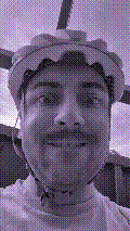a selfie of a white person, wearing either headphones or a helmet, making an odd expression. the photo is edited to be colorized into a monochrome purple-ish color palette.